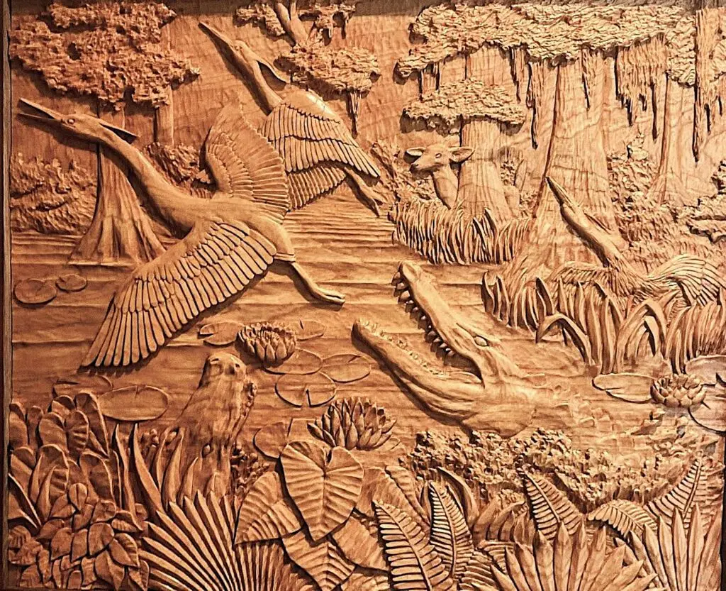 Gary Cota's hand-carved, wood relief of a swamp scene with two alligators going after herons as a deer watches