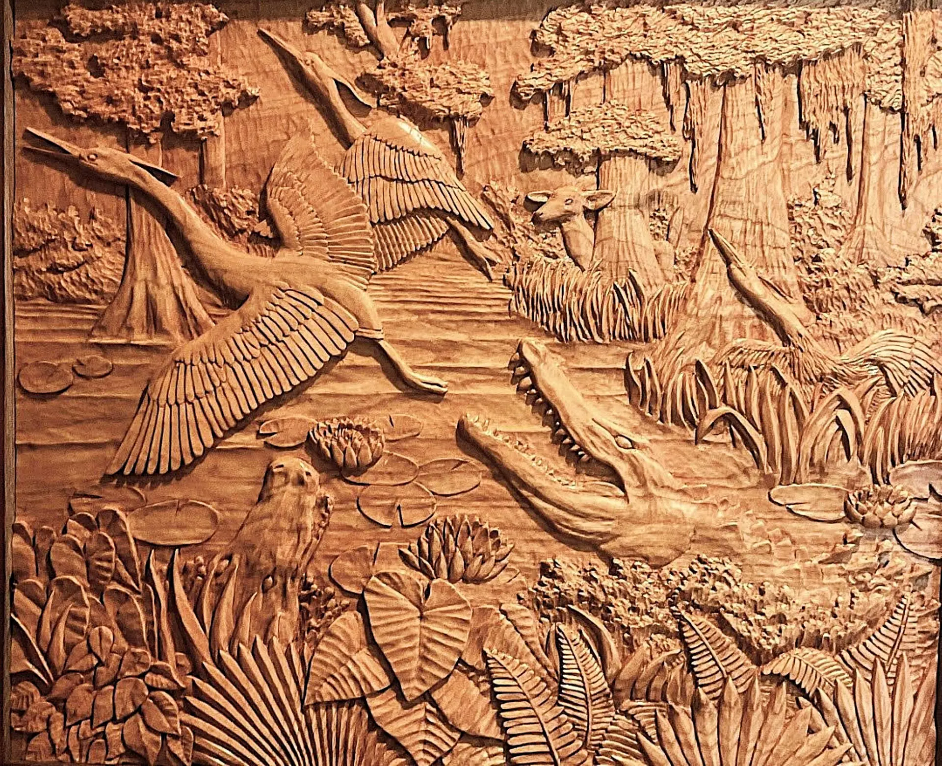 Gary Cota's hand-carved, wood relief of a swamp scene with two alligators going after herons as a deer watches