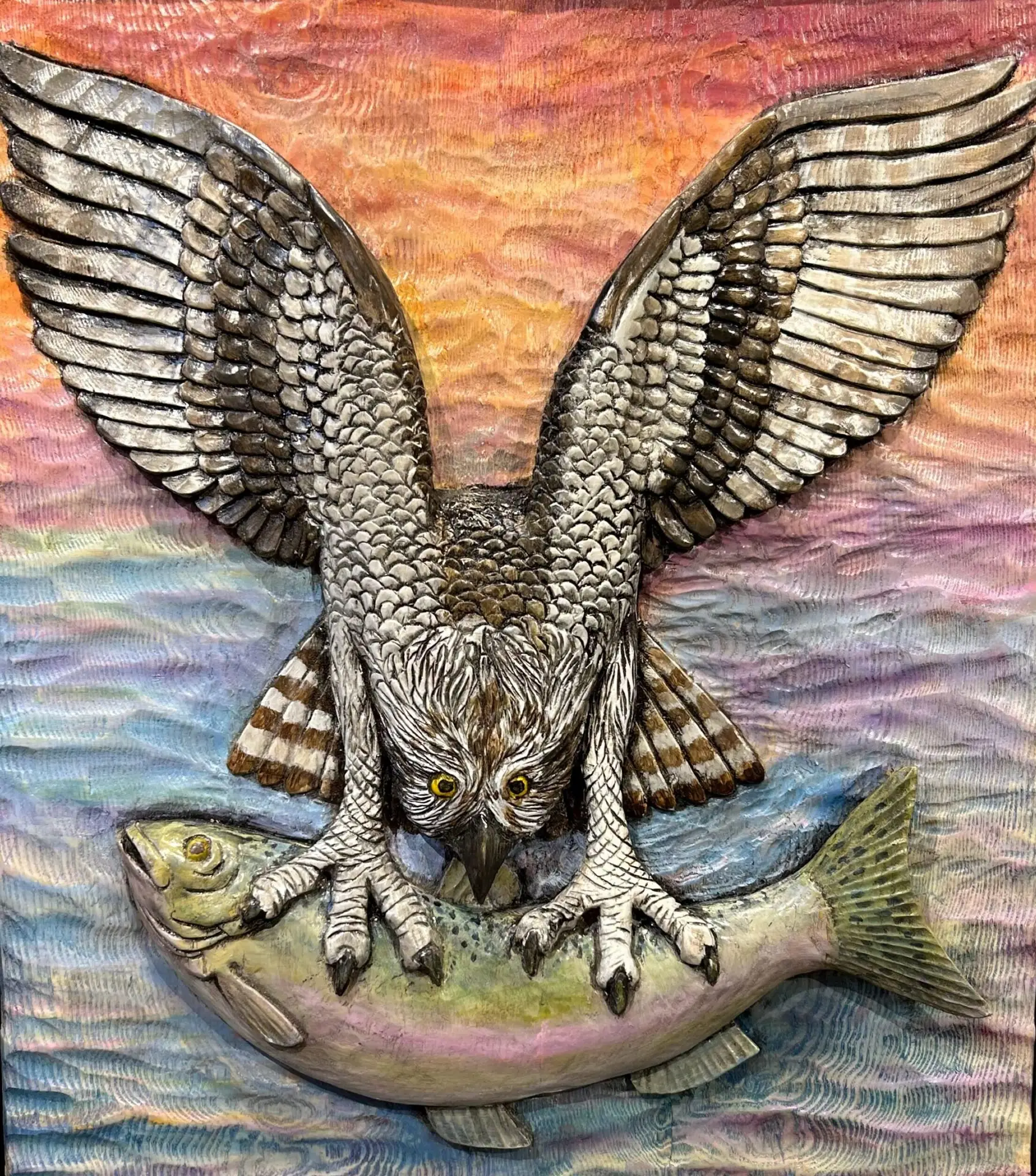 Painted wood carving of an osprey gripping a fish with its talons, wings spread wide as it prepares to fly from the water.