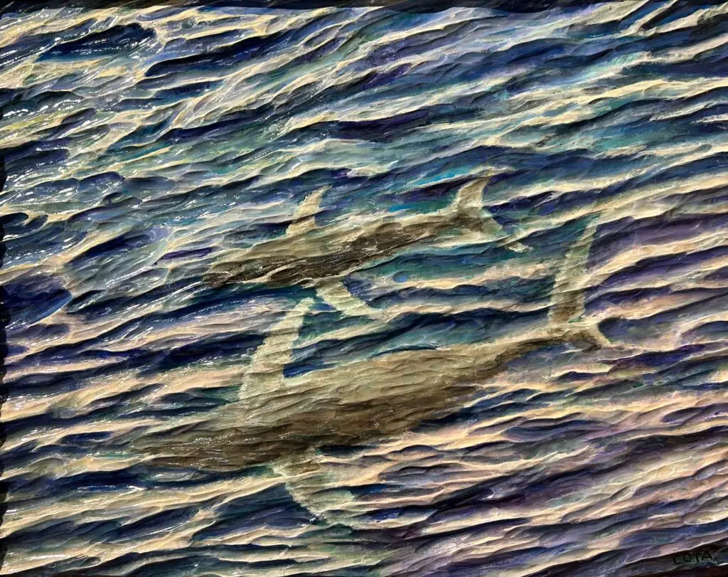 Painted wood relief of two whales swimming beneath rippling ocean water, with sunlight creating shimmering blue and white reflections