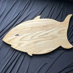 Shark-shaped hardwood cutting board with natural wood grain.