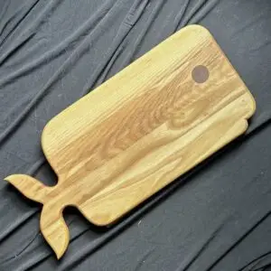 Whale-shaped hardwood cutting board with natural wood grain.