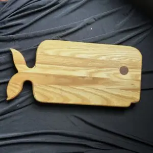 Whale-shaped hardwood cutting board with natural wood grain.
